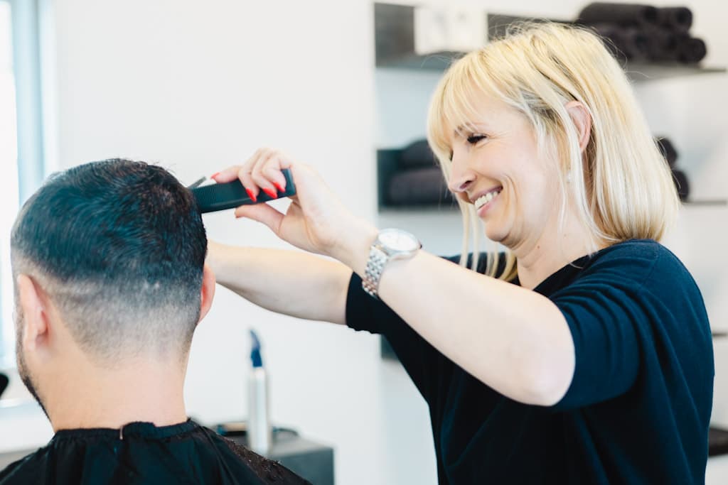 Friseurin von JJ Hair & Style föhnt und stylt einen Kunden im hellen Salon in Stemwede