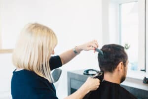 Friseurin schneidet die Haare eines Kunden im Salon