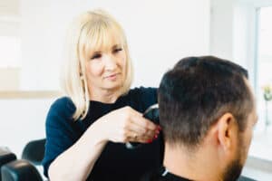 Friseurin arbeitet an einem präzisen Herrenhaarschnitt